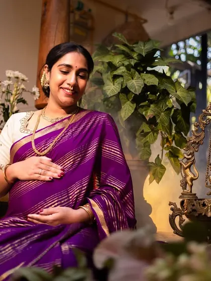 A close-up, gentle portrait of an expecting mother cradling her bump, surrounded by the soft focus of flowers, emphasizing the moment's tenderness.