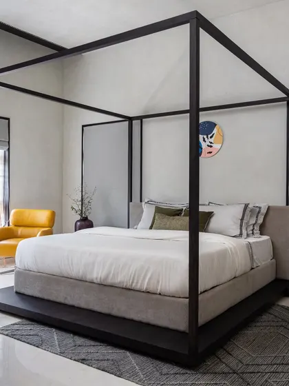 A second look at the four-poster bed, highlighting its strong, clean lines and the soft, neutral upholstery. This design creates a sanctuary that feels both grand and intimate.