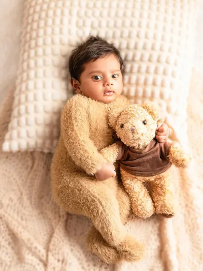 A close-up of this sweet newborn in his teddy bear outfit. The soft lighting and cozy props create a safe and comfortable environment for these precious first portraits.