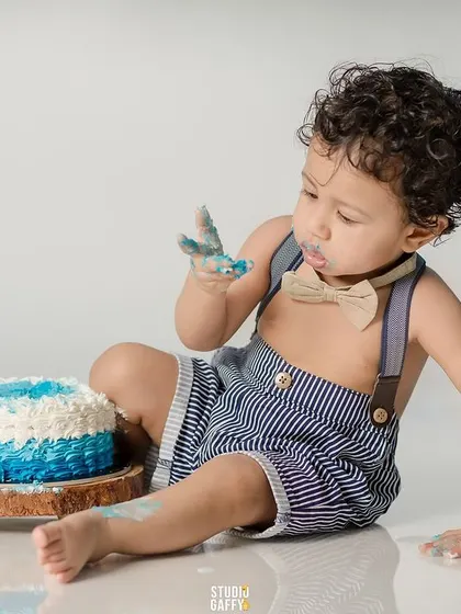 A curious first taste of frosting during a blue and white themed cake smash session.