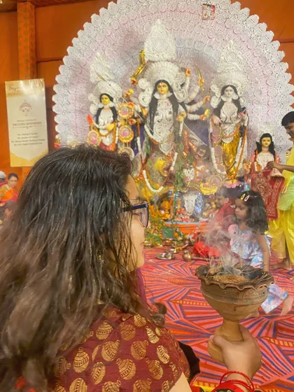 A mother and child participating in a Dhunuchi Naach ceremony during Durga Puja. This is a great example of event photography, capturing cultural traditions and family moments together.