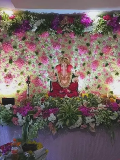 A full floral wall of pink and white flowers serves as a stunning backdrop for this Ganpati setup. The wide arrangement provides a grand and immersive floral experience for your home celebration.