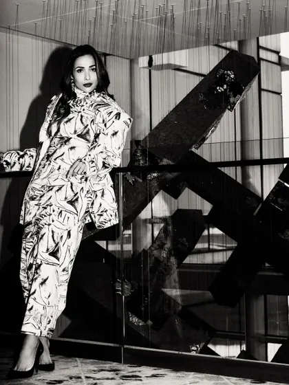 A full-length black and white shot of Malaika Arora. The geometric background and strong shadows create a high-fashion, graphic feel.