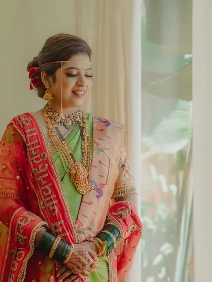 A quiet moment of reflection for the bride as she stands by a window, the soft light illuminating her beautiful attire and jewelry.