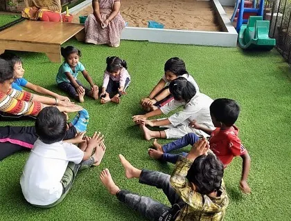 A teacher leads by example, participating in the yoga stretches with the children. This encourages them and shows that wellness is for everyone.