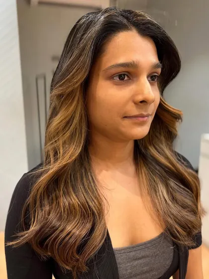 A beautiful shot of the face-framing balayage. The highlights are strategically placed to illuminate her features and add dimension.