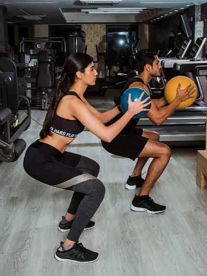 A high-quality shot of a partner squat with medicine balls, emphasizing our focus on form and community.