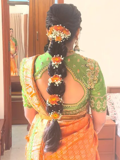 A stunning bubble braid adorned with sections of fresh orange and white flowers. This is a modern take on the traditional floral poola jada.