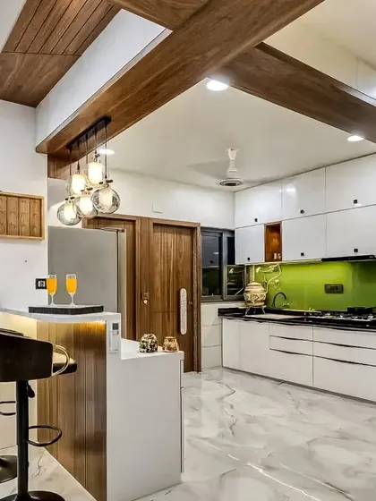This spacious open-concept kitchen features a large breakfast bar with comfortable seating. The design uses a mix of white cabinetry, a vibrant green backsplash, and wooden ceiling beams.