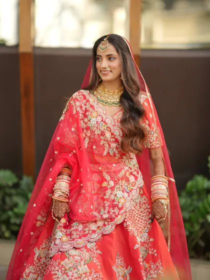 A candid moment of the bride walking, her red lehenga flowing around her. The makeup is designed to look beautiful from every angle, in every moment.