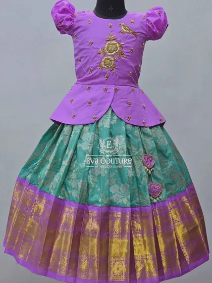 A lilac peplum top with gold bird motifs embroidered on the front. This adds a charming and unique detail to the pattu pavadai.