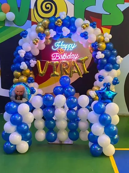 A complete Boss Baby themed setup for Virat's 9th birthday. The decoration includes a balloon arch, pillars with character toppers, and a neon sign.