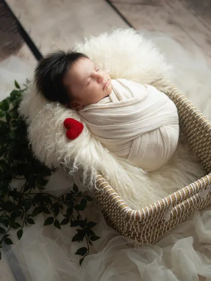 A tiny felt heart adds a touch of love to this simple and sweet newborn setup. The baby is wrapped snugly in a neutral swaddle, resting in a soft, cozy basket.