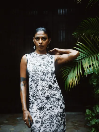 A striking portrait of Anasuya Sengupta against a backdrop of lush greenery. Her direct gaze is powerful and engaging.