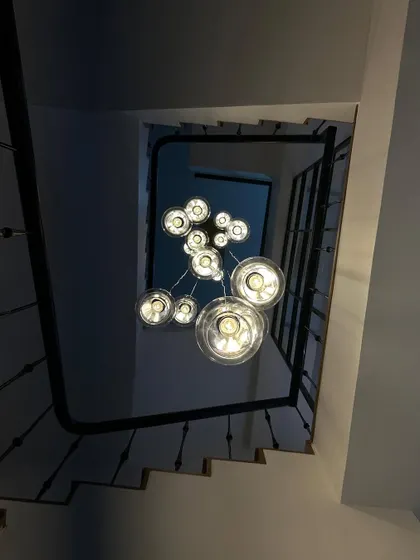Looking up through a spiral staircase at a cascading cluster of glass pendant lights. This view highlights how lighting can be a sculptural element in a home.