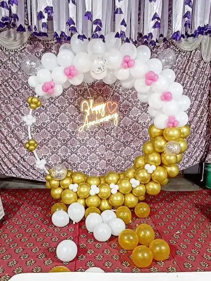 The gold and white anniversary balloon arch, accented with small pink and white balloon flowers for a touch of sweetness.