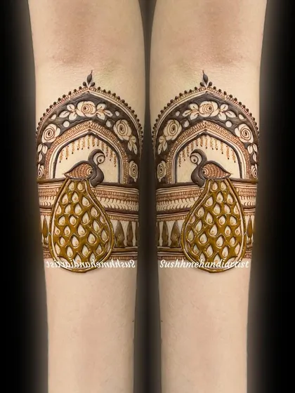 A delicate and beautiful arm band featuring two peacocks in a floral arch.