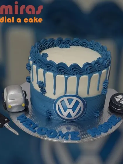 A sleek cake to celebrate a new car. This design features the Volkswagen logo, a fondant car, and keys, with the message "Welcome Home," making it a perfect congratulatory gift.