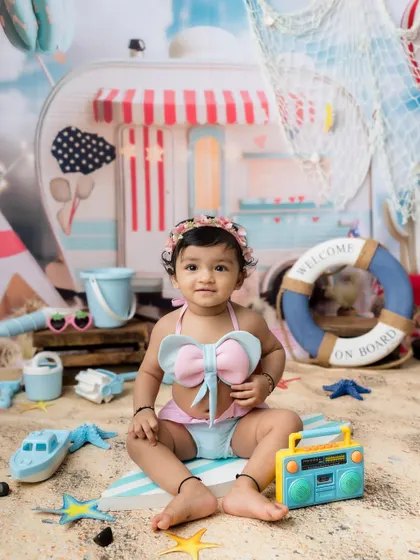 A sweet baby girl enjoying her own beach day in a cute bow swimsuit.
