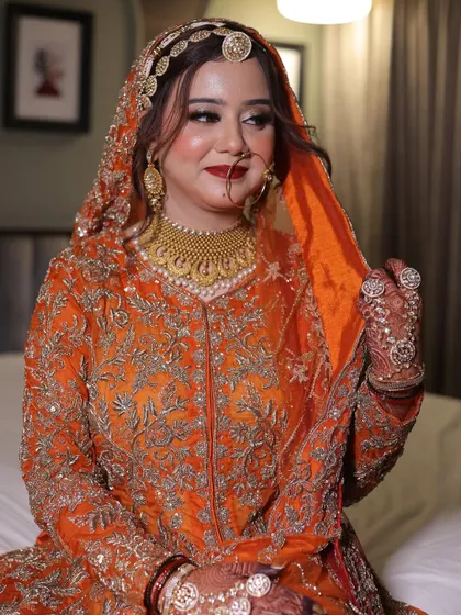 A happy and radiant bride, Ashana, on her Nikkah day. Her unique orange outfit is complemented by soft, glamorous makeup.