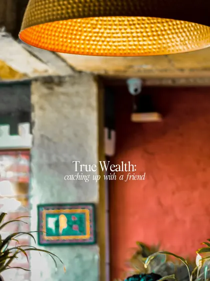 An abstract shot of a cafe interior with the theme "True Wealth: catching up with a friend." This piece uses a warm, inviting atmosphere to evoke the feeling of connection.