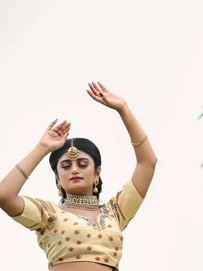 An artistic pose capturing the elegance of the cream lehenga against a simple sky backdrop.