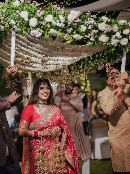 The bride's grand entrance under a magnificent phoolon ki chadar, held by her loved ones. We designed this floral canopy to be a beautiful frame for this emotional moment.