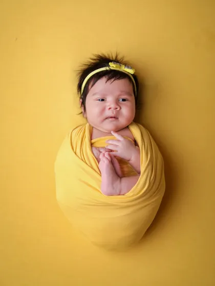 A classic potato sack pose, where the baby is snugly wrapped to feel secure. This pose is perfect for showing off their cute face and tiny feet.