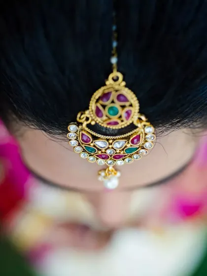 A top-down detail shot of the bride's 'maang tikka', showcasing the intricate design of her jewelry.