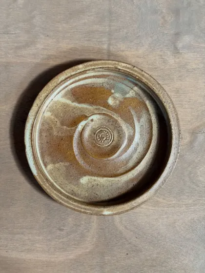 A handmade stoneware plate with a rustic, earthy glaze. The spiral pattern is a signature of my thrown work, and the unique glaze variations mean no two plates are ever the same.