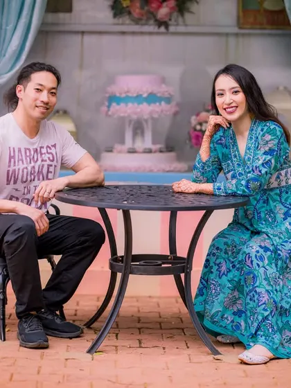 A casual portrait at a cafe-style table. The couple's relaxed poses and the charming setting create a very natural and authentic pre-wedding photo.
