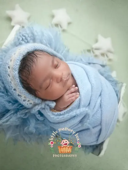 A close-up of this little one, showing the detail of the knitted bonnet and the soft, fluffy layers they are resting on. It's all about comfort and coziness.