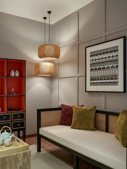 Ambient lighting is key to creating a mood. In this cozy nook, woven bamboo pendant lights cast a warm, inviting glow, highlighting the texture of the paneled wall.