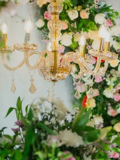A beautiful crystal chandelier hangs amidst a sea of flowers, a perfect fusion of glamour and natural beauty.