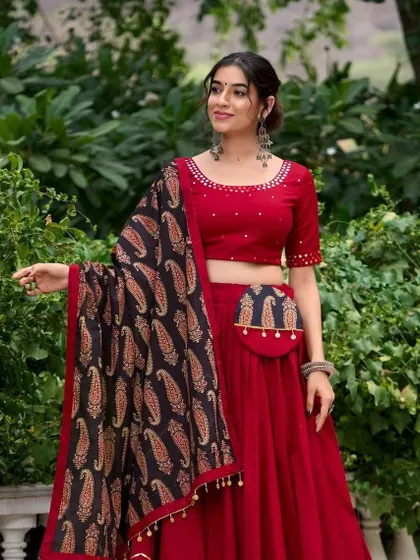 This image shows the same red chaniya choli but with a matching embroidered potli bag attached at the waist, a stylish and practical accessory for Garba.