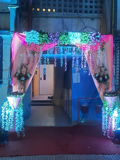 A lovely entrance for a house party at night. The pink drapes are decorated with hanging flowers and illuminated with blue lights.