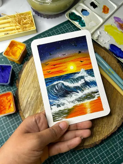 Holding up my finished beach sunset polaroid painting. The colors of the sky and their reflection in the water are my favorite part.