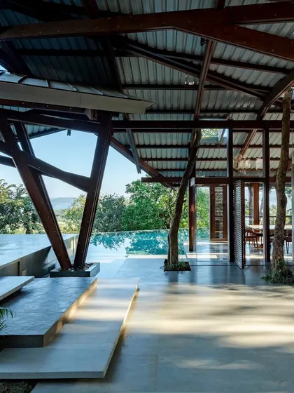 The Lateral Verandah House finds its footing on a sloping hill in Lonavala, its unique timber frame creating a dialogue with the landscape. We used raw basalt walls to ground the structure, a nod to the region's architectural history, creating a space that feels both of the earth and elegantly light.