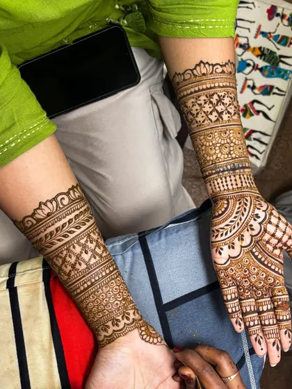 This design showcases beautiful symmetry and detailed cuff work on the wrists. The pattern combines grids, leaves, and floral elements for a classic bridal look.