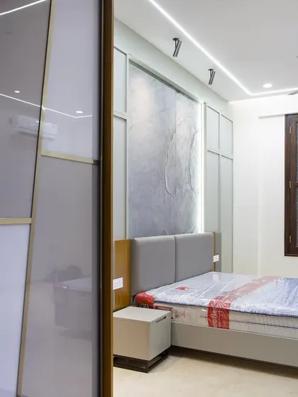 This view shows the interplay between the stone accent wall and the sleek, multi-panel sliding wardrobe. The wardrobe's design adds to the room's quiet, uncluttered feel, proving that great storage is key to a peaceful space.
