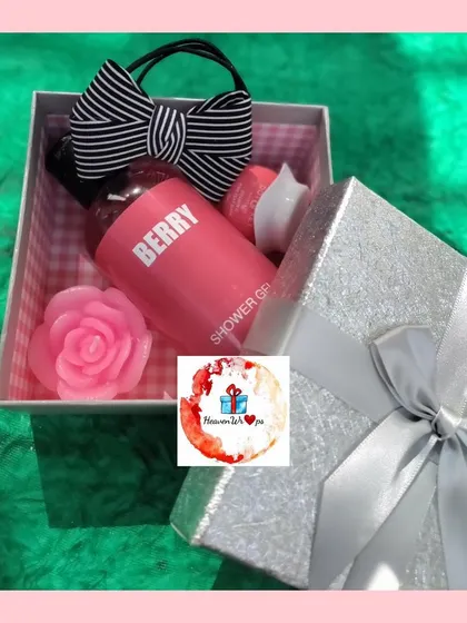 A sweet Women's Day gift box containing berry-scented shower gel, a rose-shaped soap, and a cute striped bow.