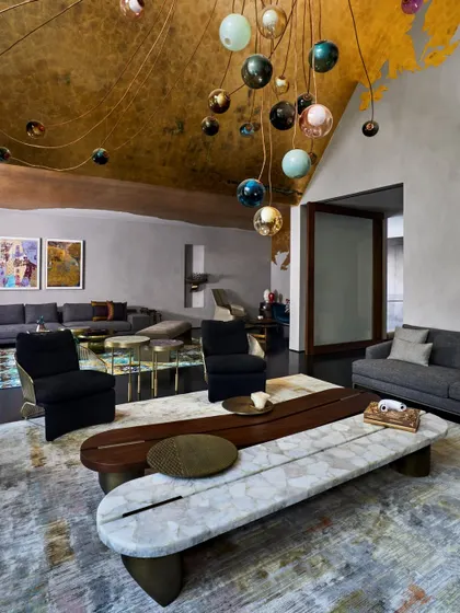The living room at Baid Residence, bathed in the soft glow of Bocci lights. The ceiling is adorned with exquisite gold leaf, and the space is furnished with pieces from Minotti and Poliform, creating an atmosphere of pure opulence.