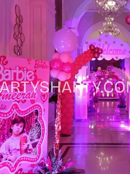 A personalized welcome banner and balloon column at the entrance of a Barbie-themed party, creating an exciting and on-theme arrival experience.
