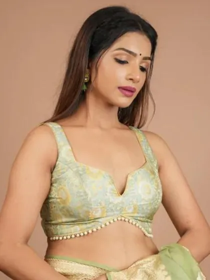 A sleeveless brocade blouse in a lovely light green, with a V-neckline and delicate pearl detailing.