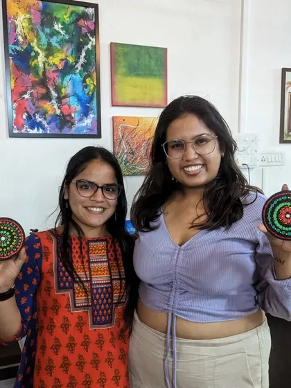 Two friends with their finished dot mandala coasters, a perfect souvenir from a fun and creative workshop.
