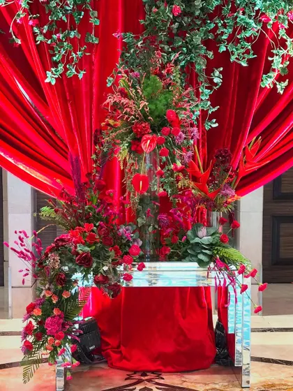An elegant red floral arrangement for a reception filled with love. I used a mix of anthuriums, roses, and cascading blooms against a backdrop of rich red velvet to create a look of pure opulence.