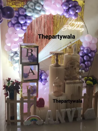A purple, pink, and silver balloon ring with a gold shimmer backdrop and 'BABY' blocks.