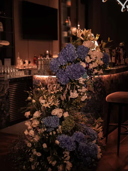 Even the bar was transformed into a statement piece. We adorned the marble countertop with cascading arrangements of blue hydrangeas and white lilies, ensuring every corner of the event felt cohesive and beautifully styled for the birthday celebration.