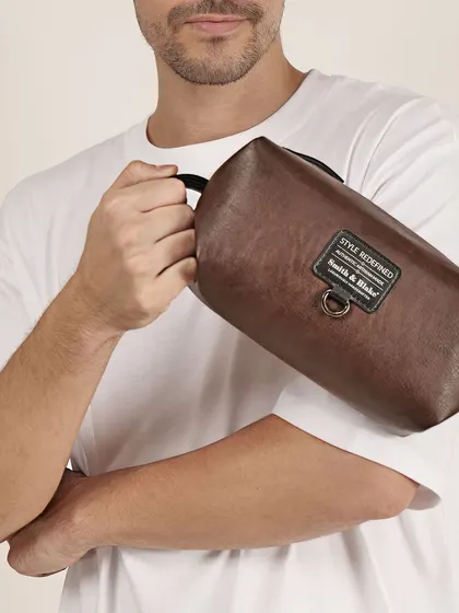 A close-up of a man holding a brown leather pouch. This highlights the product's texture and compact size, showing how it's held and used.