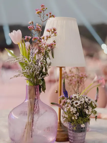 A close-up of a purple glass vase with delicate flowers, part of an elegant and charming centerpiece.